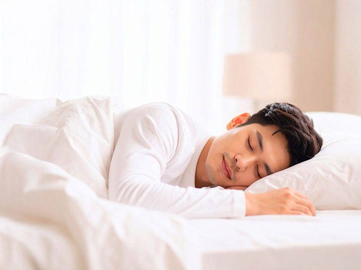 ベッドで眠る若い男性