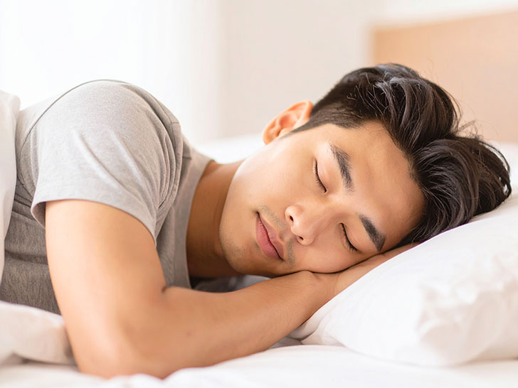 ベッドで眠る若い男性