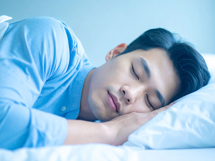 ベッドで眠る若い男性