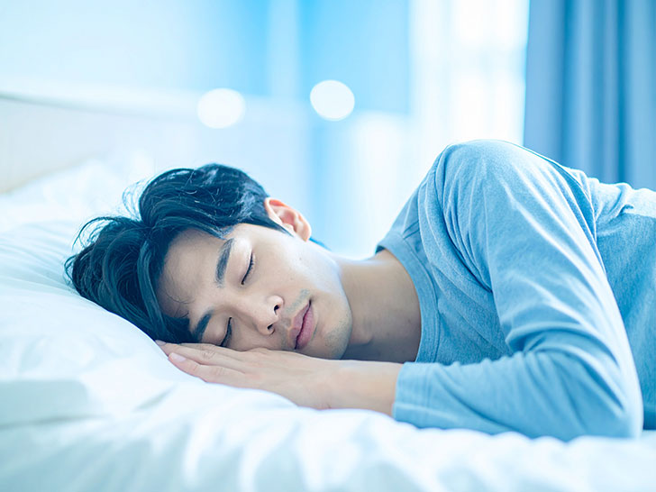 ベッドで眠る若い男性