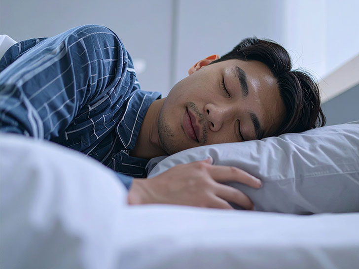 ベッドで眠る若い男性