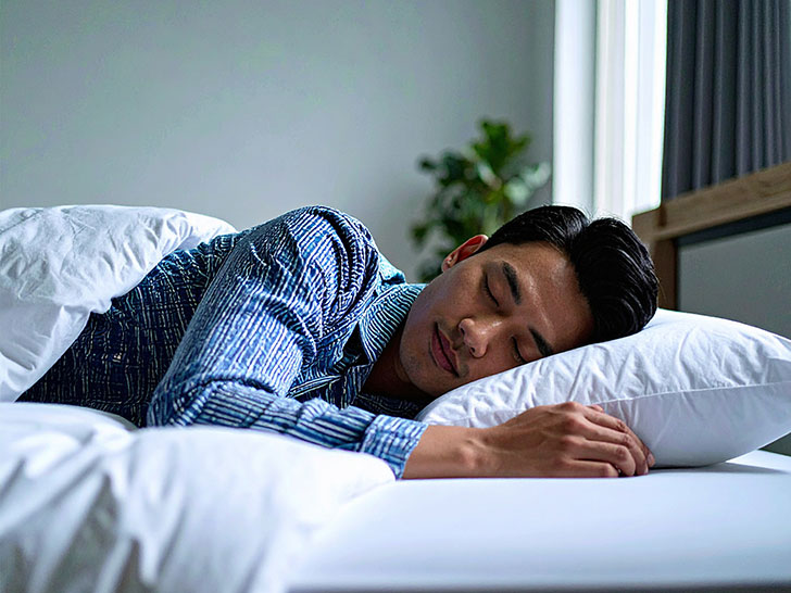 ベッドで眠る若い男性
