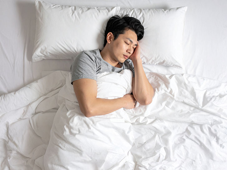 ベッドで眠る若い男性