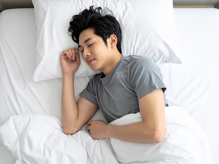 ベッドで眠る若い男性