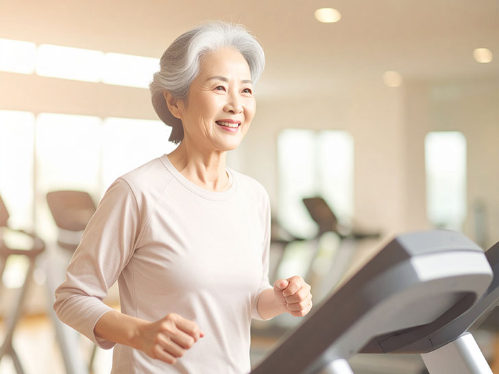 ジムのウォーキングマシンで歩くシニア女性
