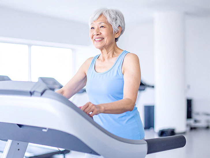ジムのウォーキングマシンで歩くシニア女性