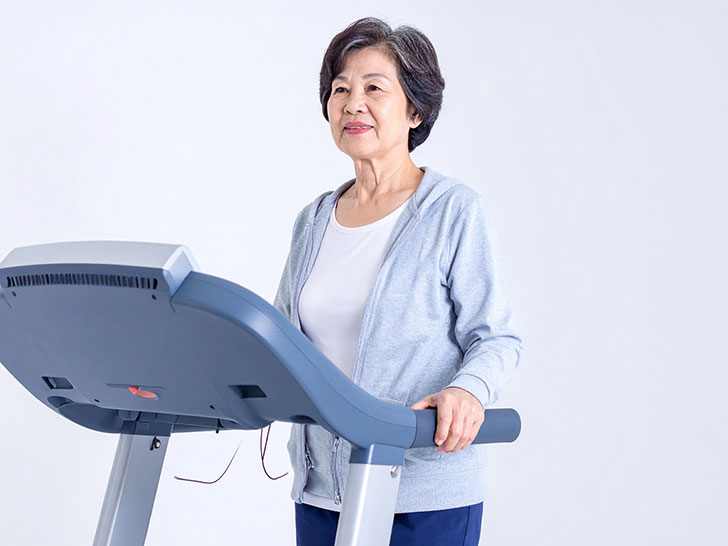 ジムのウォーキングマシンで歩くシニア女性