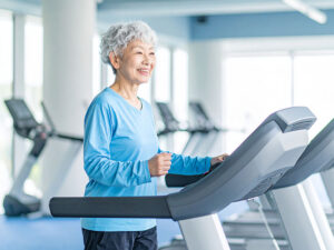 ジムのウォーキングマシンで歩くシニア女性