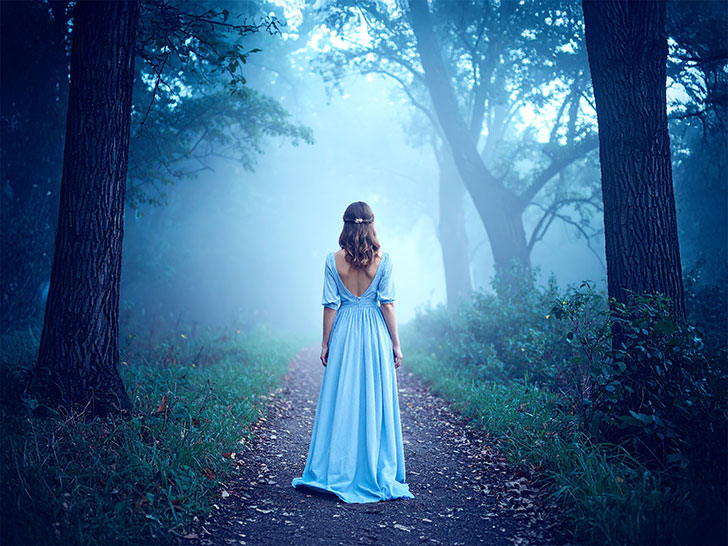 森の中に佇む若い女性の後ろ姿
