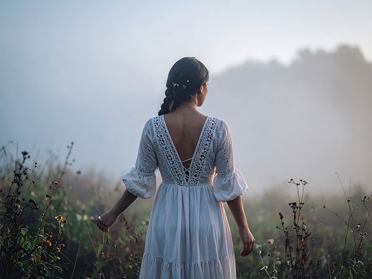 森の中に佇む若い女性の後ろ姿