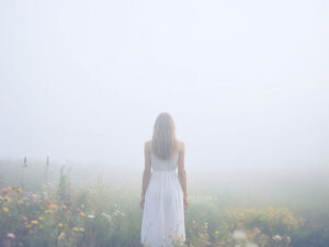 森の中に佇む若い女性の後ろ姿