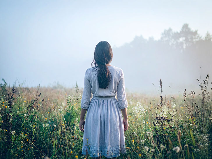 森の中に佇む若い女性の後ろ姿