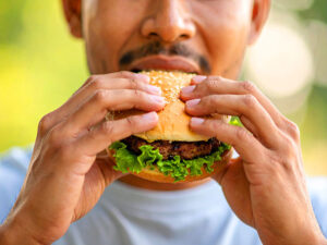 ハンバーガーにかぶりつく若い男性の口元