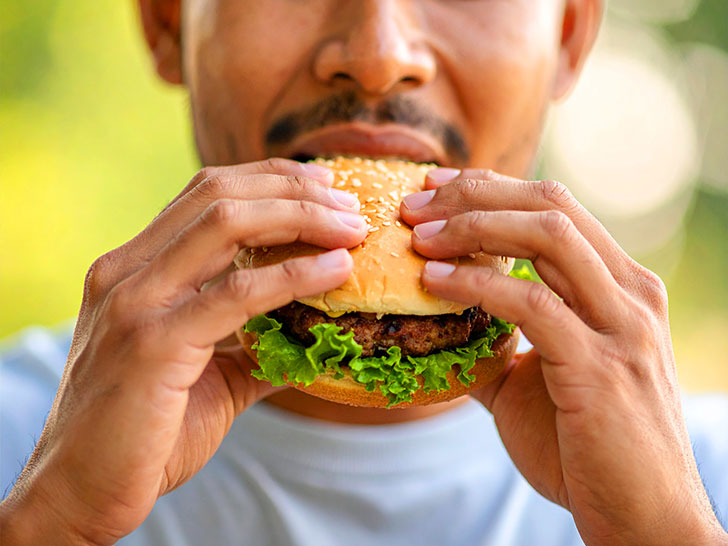 ハンバーガーにかぶりつく若い男性の口元