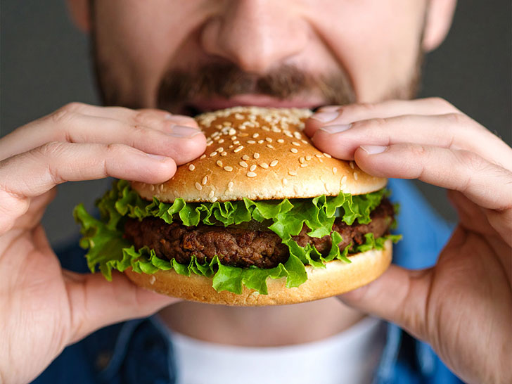 ハンバーガーにかぶりつく若い男性の口元