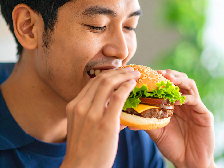 ハンバーガーにかぶりつく若い男性の口元