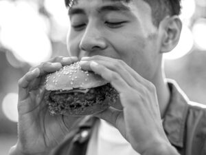 ハンバーガーにかぶりつく若い男性の口元