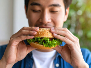ハンバーガーにかぶりつく若い男性の口元