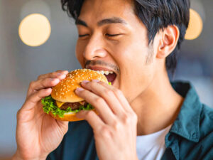 ハンバーガーにかぶりつく若い男性の口元