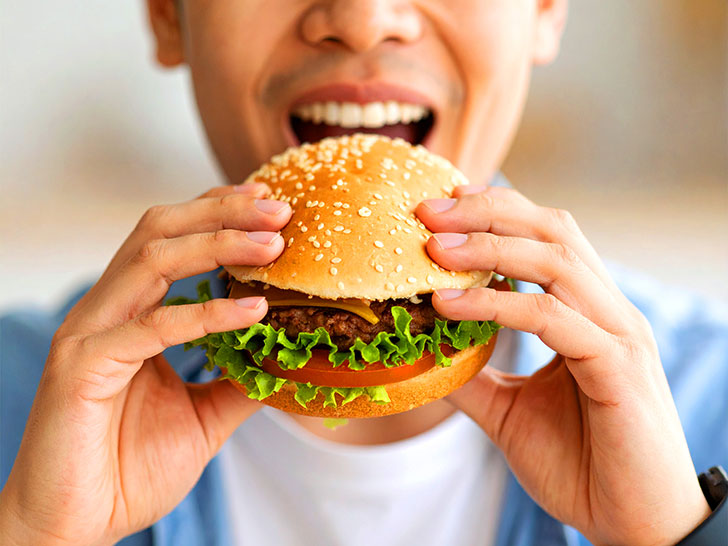 ハンバーガーにかぶりつく若い男性の口元