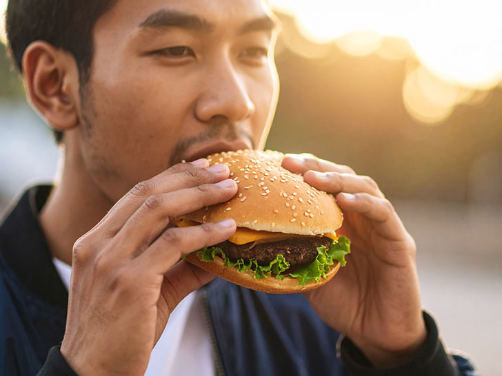 ハンバーガーにかぶりつく若い男性の口元