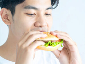 ハンバーガーにかぶりつく若い男性の口元