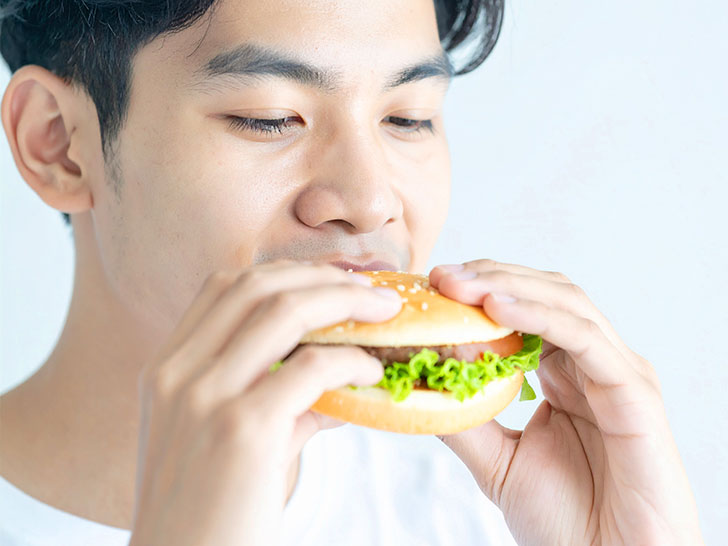 ハンバーガーにかぶりつく若い男性の口元