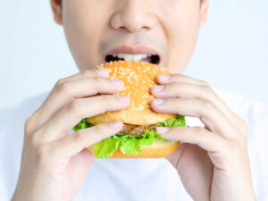 ハンバーガーにかぶりつく若い男性の口元