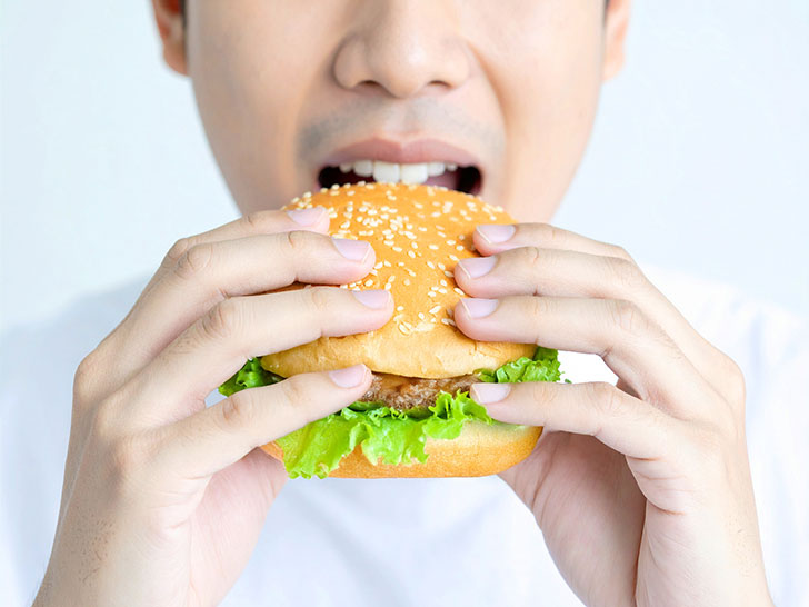 ハンバーガーにかぶりつく若い男性の口元