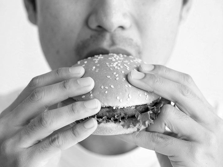ハンバーガーにかぶりつく若い男性の口元