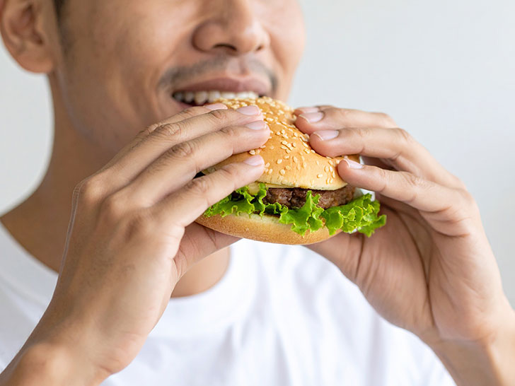 ハンバーガーにかぶりつく若い男性の口元