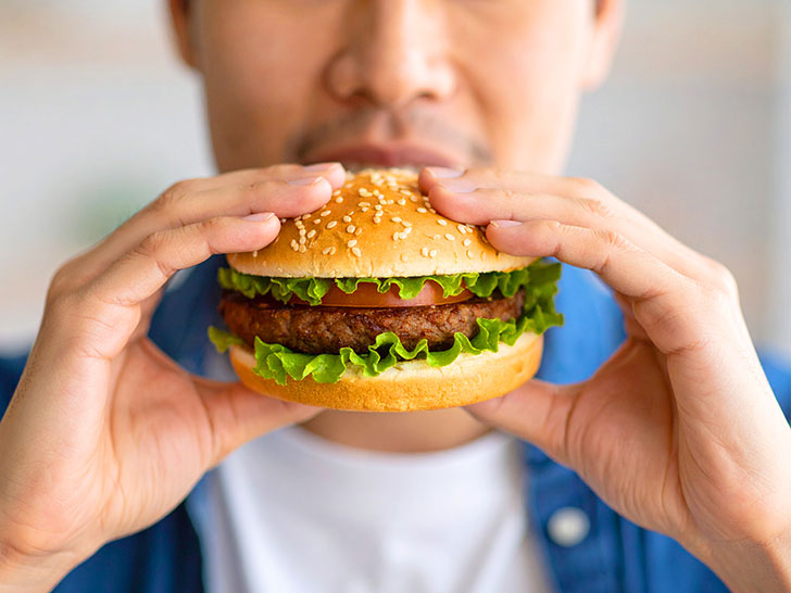 ハンバーガーにかぶりつく若い男性の口元