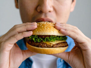 ハンバーガーにかぶりつく若い男性の口元