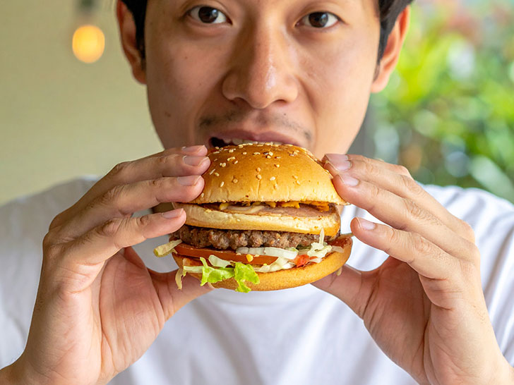 ハンバーガーにかぶりつく若い男性の口元