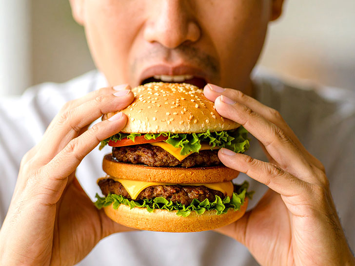 ハンバーガーにかぶりつく若い男性の口元
