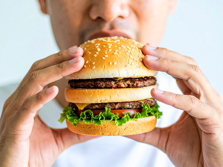 ハンバーガーにかぶりつく若い男性の口元