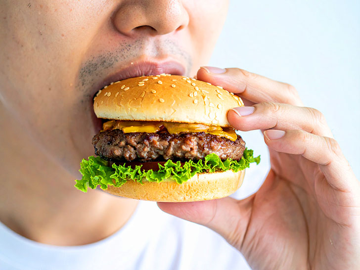 ハンバーガーにかぶりつく若い男性の口元
